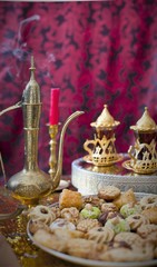 Oriental tea tray and cookies symbolising Moroccan hospitality, Islamic holidays food with decoration. Ramadan kareem. Eid mubarak. Oriental hospitality concept. Tea glasses and pot, traditional delig