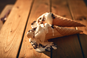 Ice cream in cones thaws on a wooden table. Ice cream in hot summer.