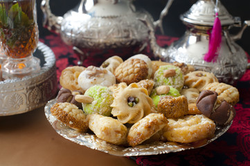 Oriental tea tray and cookies symbolising Moroccan hospitality, Islamic holidays food with decoration. Ramadan kareem. Eid mubarak. Oriental hospitality concept. Tea glasses and pot, traditional delig