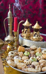Oriental tea tray and cookies symbolising Moroccan hospitality, Islamic holidays food with decoration. Ramadan kareem. Eid mubarak. Oriental hospitality concept. Tea glasses and pot, traditional delig