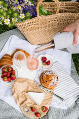 Man's hand pouring rose wine into glasses, summer picnic