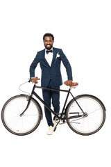 Obraz premium cheerful african american man in suit standing near bicycle isolated on white