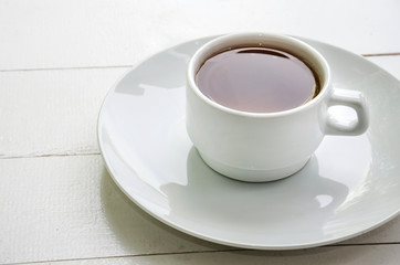 Fototapeta na wymiar white cup of tea in a white plate on a white background, close up