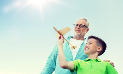 family, generation, future, dream and people concept - happy grandfather and grandson with toy airplane over blue sky