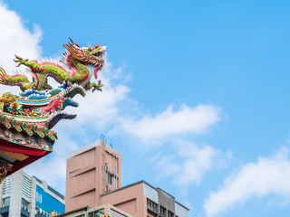 Looking up dragon sculpture on top of chinese temple roof against the blue sky and clouds with copy...