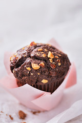 Chocolate muffin with hazelnuts in a pink paper viewed from above. Copy space