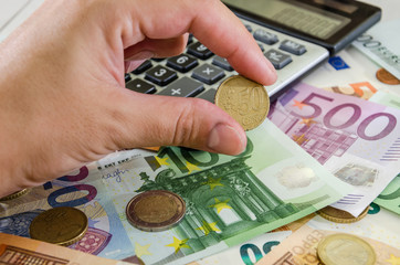 Hand holds a coin on the background of the calculator, euro, close-up