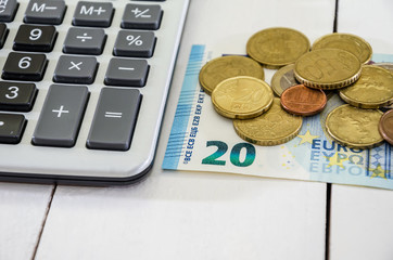 20 euro banknote, coins and calculator on white background