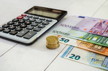 euro banknotes, coins and calculator on white table