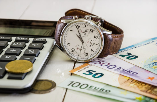wrist watch with euro, coins and calculator on the table