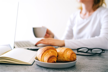 Croissants with coffee on the office table.  Business breakfast concept