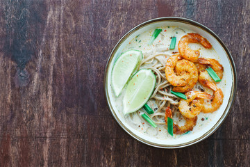 Coconut curry soup with noodles and shrimps in bowl. Asian cuisine concept