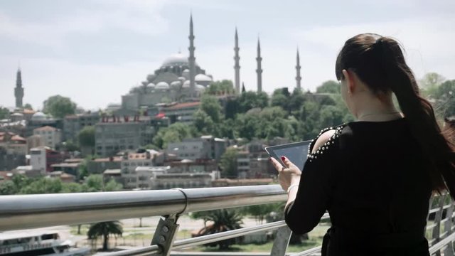 Girl tourist stands and takes pictures on the tablet beautiful sights of the city. Turkey