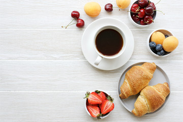 Coffee, croissants and berries for breakfast on white wooden background. Copy space