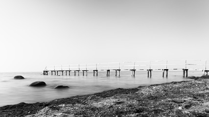 Long exposure side view of a wooden bathing jetty in monochrome