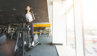 Fototapeta na wymiar Workout in gym. Woman exercising on cross trainer
