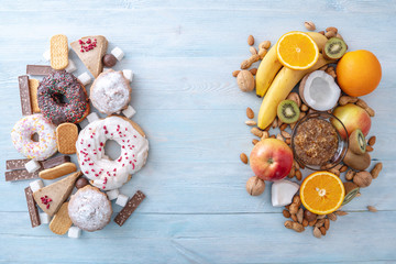 Unhealthy and healthy sweets. Organic and dietary food. Fruits and nuts vs donuts cupcakes and candy. Top view