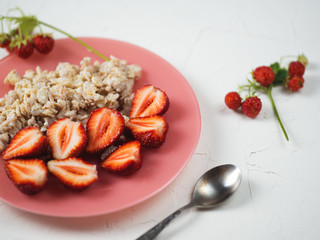 Oatmeal with strawberries on a white table . Healthy and tasty Breakfast