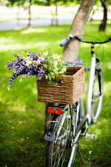 New city bicycle with bouquet of flowers in wicker basket
