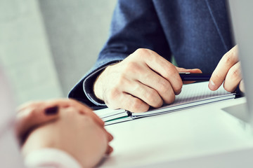Close up focus on male hand holding ballpoint and listening to colleague or employee. Corporate...