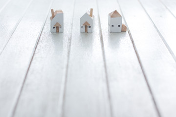 Miniature house model on white wood background, copy space