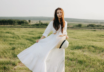 Beautiful carefree long hair asian girl in white clothes and straw hat enjoys life in nature field...