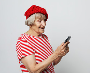 Naklejka premium old grandmother is talking to her grandchildren by phone, smiling and greeting them.