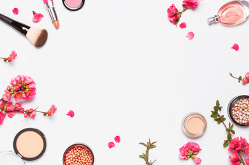 Different makeup cosmetic. Ball blush rouge face powder lipstick concealer bottle of perfume eyeshadow makeup brush spring pink flowers on light background top view flat lay. Beauty fashion background