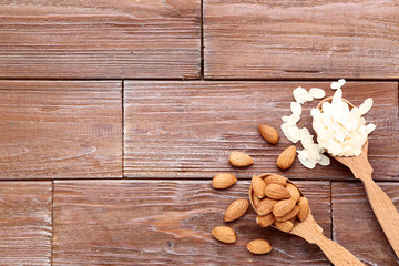 Almonds in spoons on brown wooden table