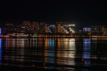 Obraz premium Night Gelendzhik landscape with reflection of city lights in sea water, copy space