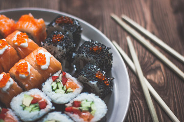 Sushi Maki Rolls with Chopsticks on a Wooden Platter with Wasabi - Viewed from Above Isolated on Grey Wood Background.