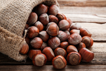 Ripe hazelnuts in sackcloth on brown wooden table