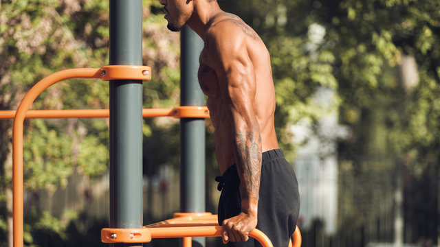 Muscular Man Doing Triceps Dips On Parallel Bars