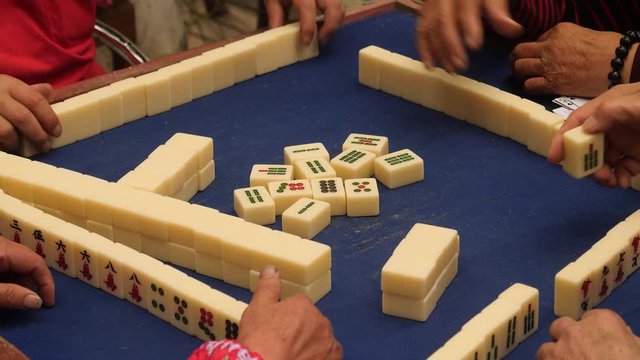 Mahjong game, closeup of hands picking tiles.