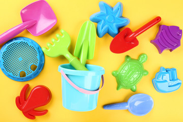 Plastic beach toys on yellow background