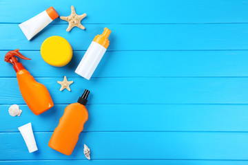 Sunscreen bottles with seashells on blue wooden table