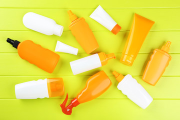 Sunscreen bottles on green wooden table
