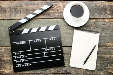 Clapper board with cup of coffee and notebook on grey wooden table
