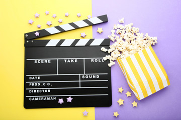 Clapper board with popcorn on colorful background