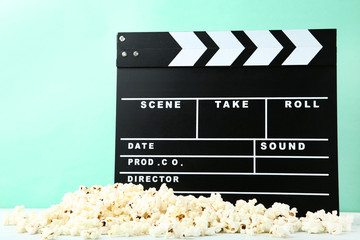 Clapper board with popcorn on mint background