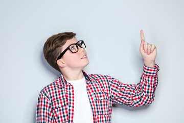 Portrait of young boy in glasses on grey background