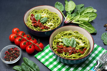 Pasta with spinach creamy sauce, sun-dried tomatoes and cheese. Useful tasty homemade food. Selective sharpness, shallow depth of field. Author's retouch