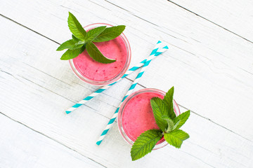 Two glasses of berry smoothies on the white wooden table