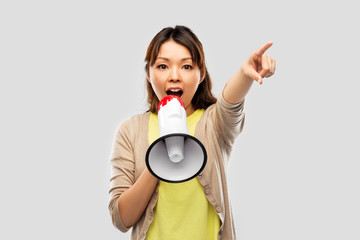 communication, feminism and human rights concept - asian young woman speaking to megaphone over...