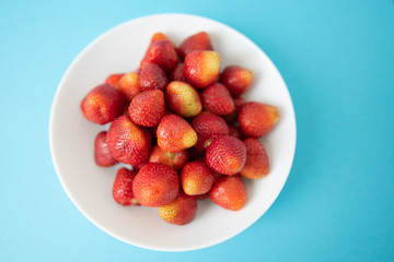summer berry. juicy red strawberries on white plate on blue background. Delicious breakfast snack. Vegetarian food. useful vitamins. isolated.