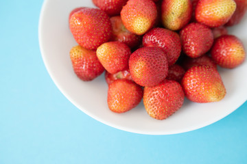 summer berry. juicy red strawberries on white plate on blue background. Delicious breakfast snack. Vegetarian food. useful vitamins. isolated.