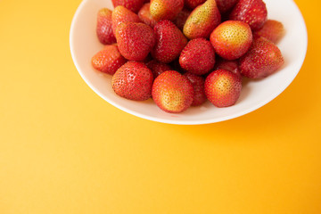 summer berry. juicy red strawberries on white plate on yellow background. Delicious breakfast snack. Vegetarian food. useful vitamins. isolated.