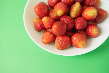 summer berry. juicy red strawberries on white plate on green background. Delicious breakfast snack. Vegetarian food. useful vitamins. isolated.