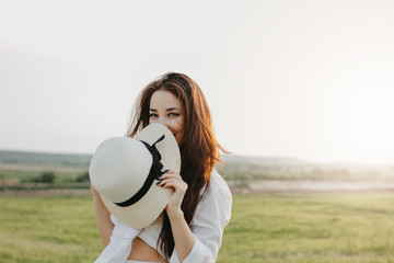 Portrait of charming carefree long hair asian girl in white clothes and straw hat enjoys life in...