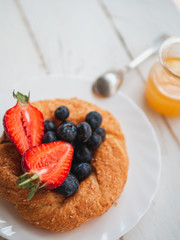 Fresh bagel with blueberries and strawberries on a white background. English summer breakfast. Vertical shot